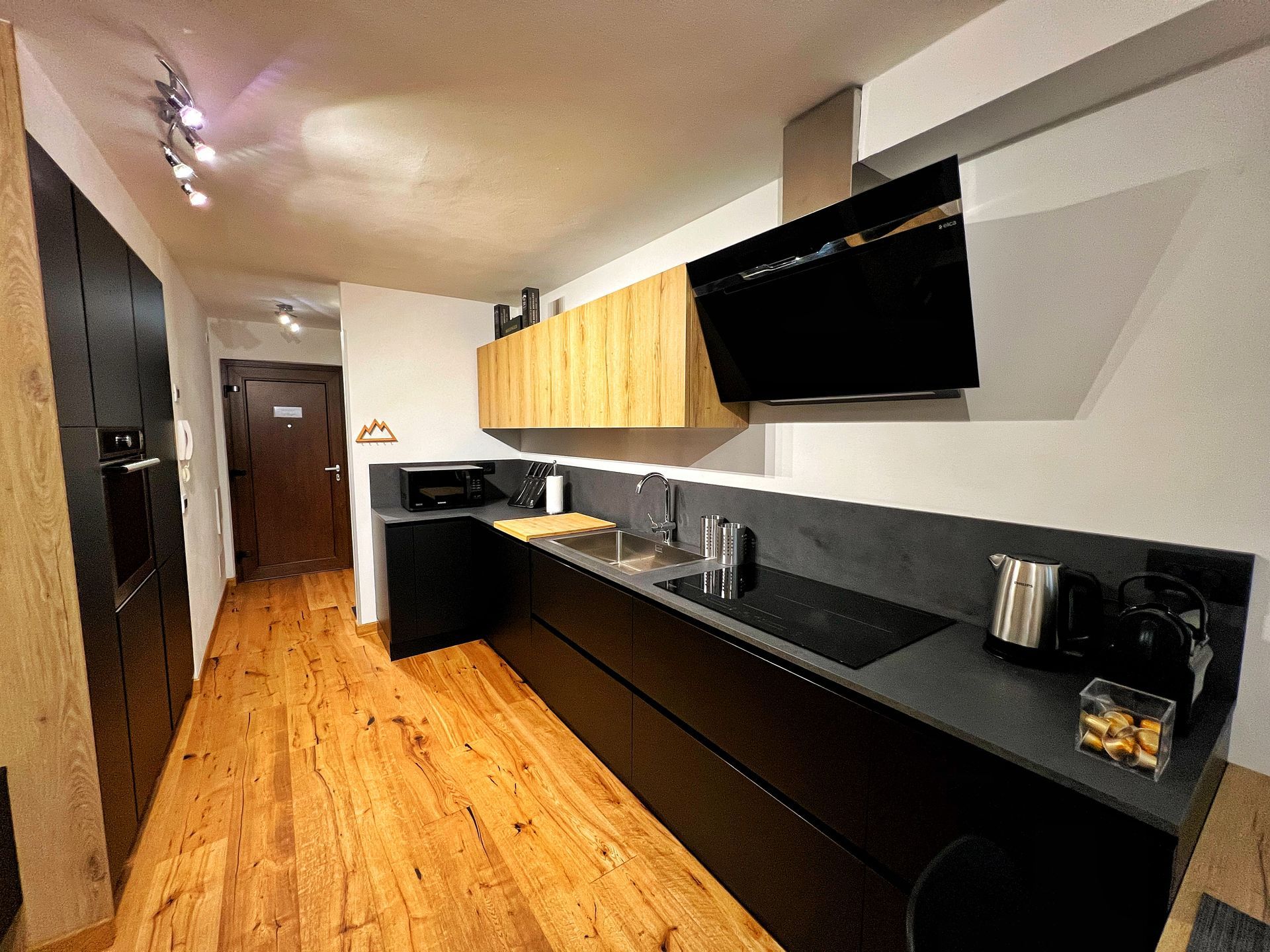 Una cucina con pavimenti in legno e mobili neri