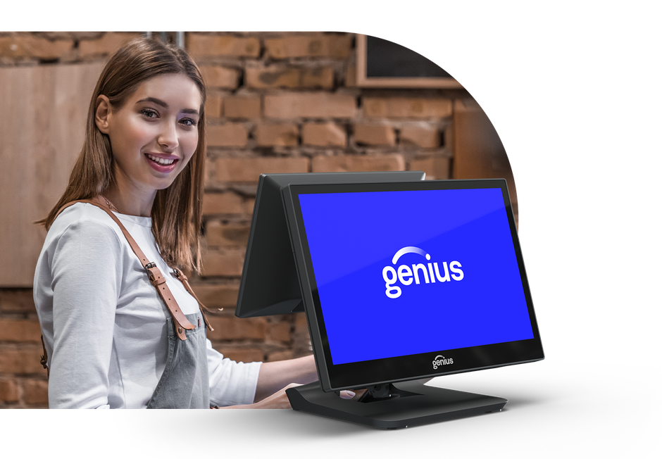 Woman smiling at a computer monitor displaying the Genius logo in a brick-walled office
