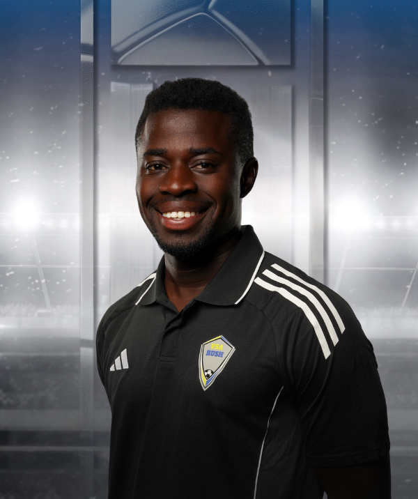 Smiling athlete in a black jersey with white stripes, standing in front of a stadium backdrop
