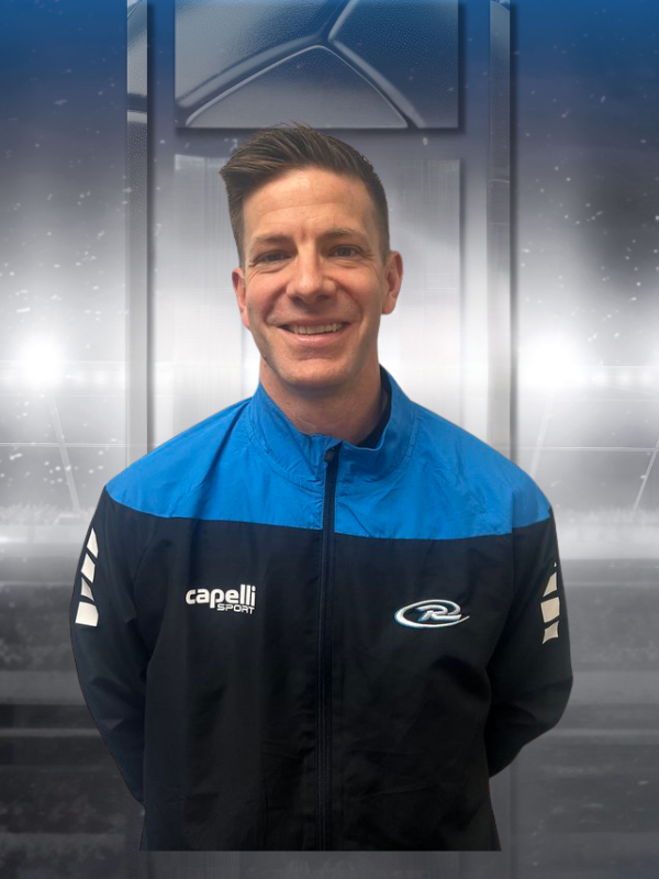 Smiling athlete in a blue-and-black jacket standing indoors against a metallic backdrop