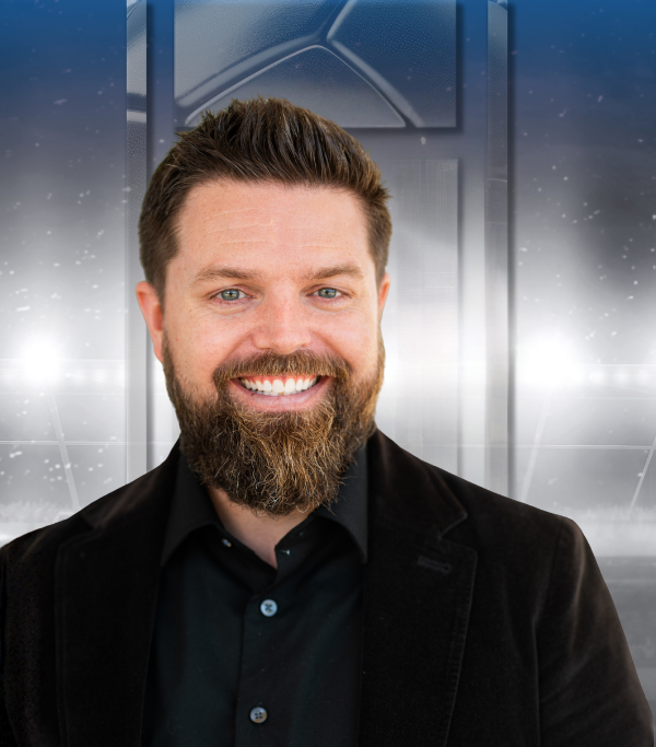 Smiling man with a beard in a black shirt against a metallic, futuristic background