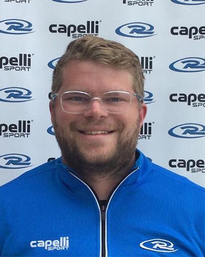Smiling man in blue Capelli Sport jacket in front of a Capelli Sport backdrop