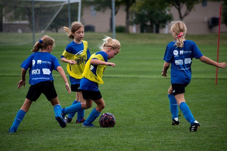 Children playing soccer on a grassy field, with one in a yellow jersey dribbling the ball