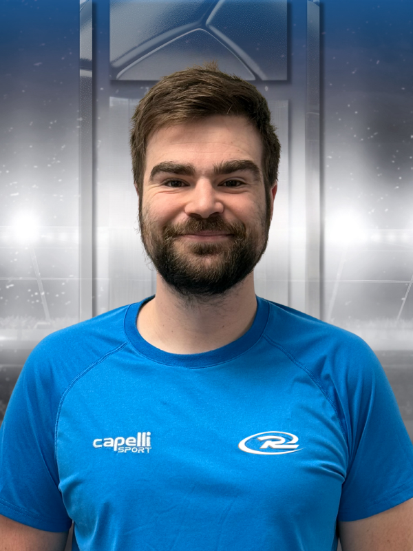Smiling man in a bright blue athletic shirt against a gray indoor backdrop