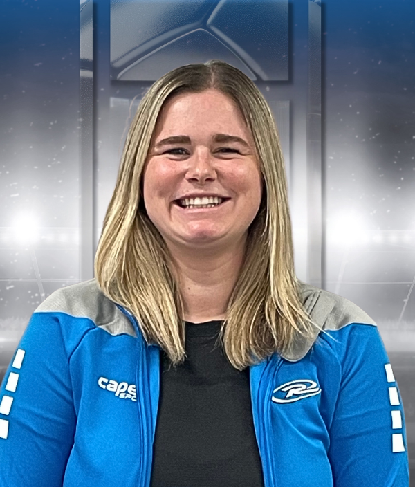 Smiling person in a blue jacket with arms crossed against a metallic background