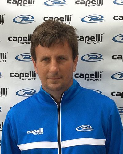 Man in blue Capelli jacket standing before a Capelli logo backdrop