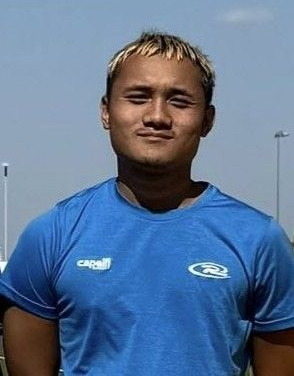 Young person in a blue athletic shirt standing outdoors under a clear sky