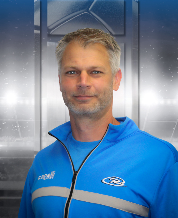 Man in blue jacket standing in front of a metallic elevator background