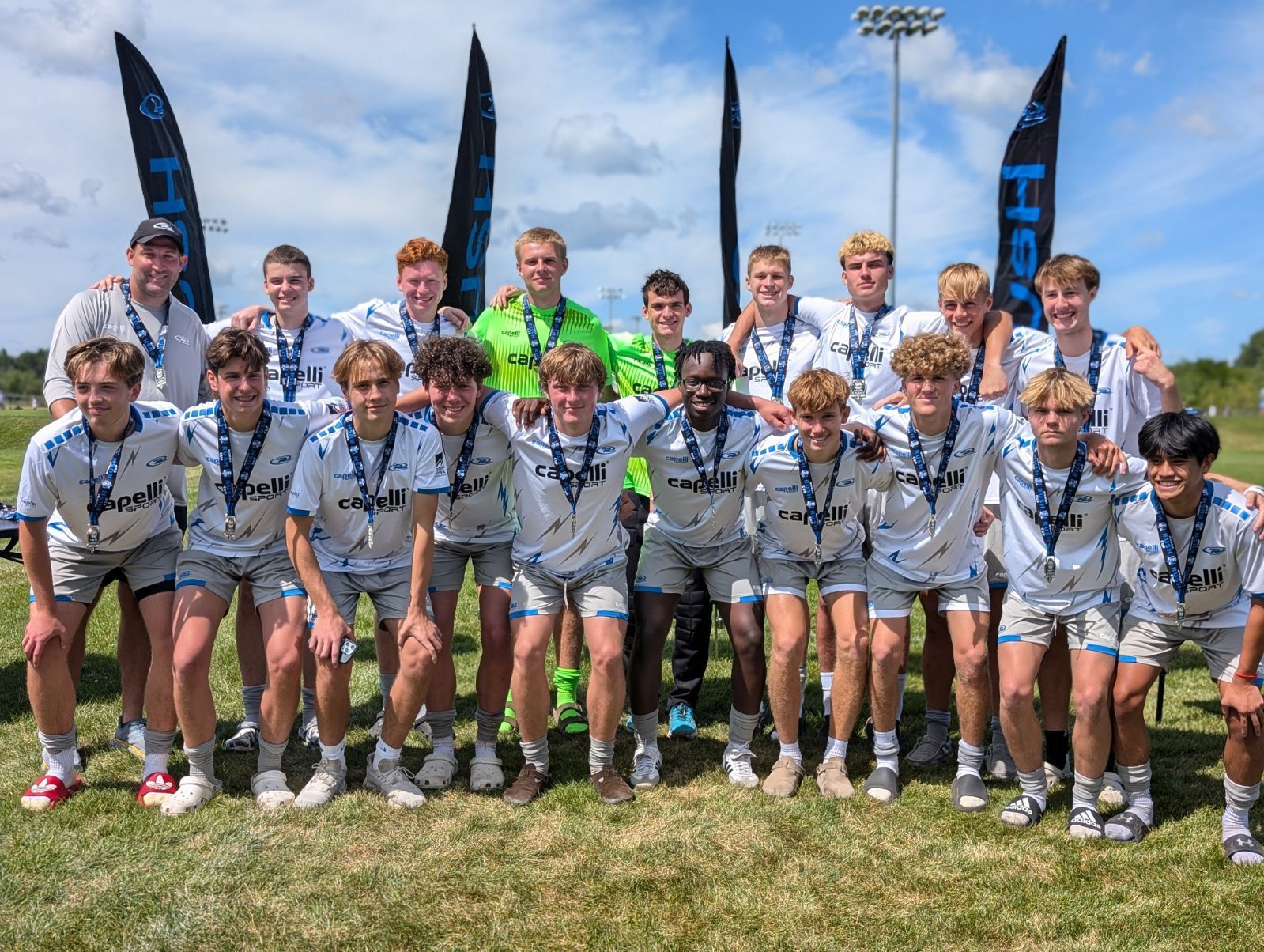 Youth sports team posing outdoors in white uniforms with paddles behind them under a sunny sky