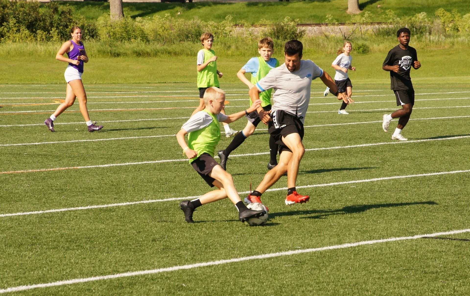 Soccer players sprinting and kicking a ball on a grassy field during a game
