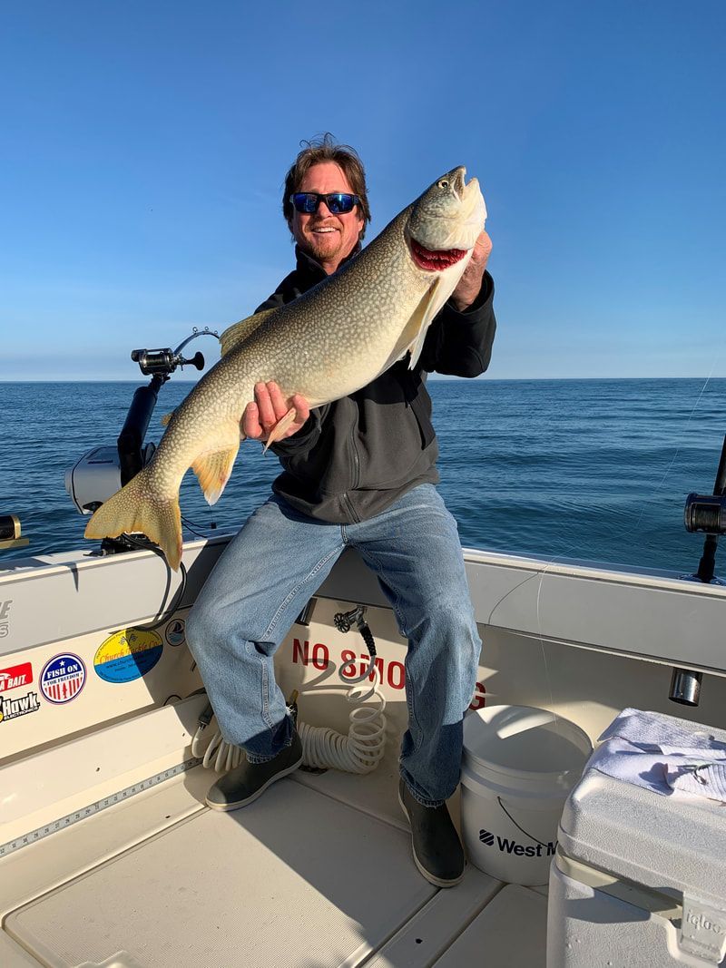 A man is holding a large fish on a boat.