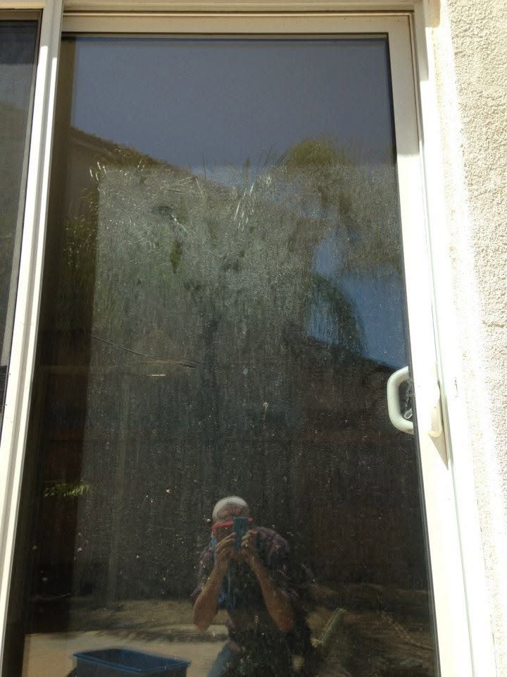 Dirty glass door reflecting a person taking the photo outdoors.
