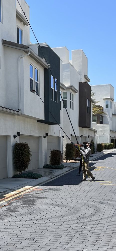 Narrow residential street with white townhouses and a person walking a bicycle in sunlight