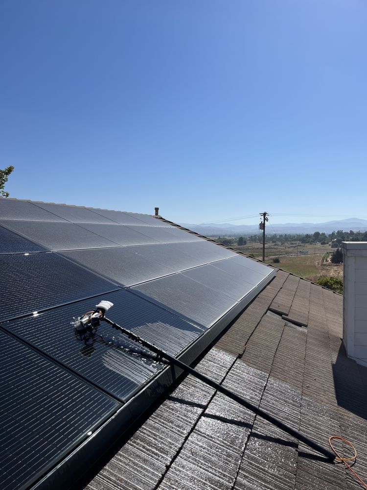 Solar panels on a rooftop under a clear blue sky, with a maintenance tool resting on one panel.