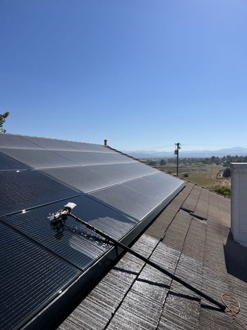 Solar panels on a rooftop under a clear blue sky, with a maintenance tool resting on one panel.