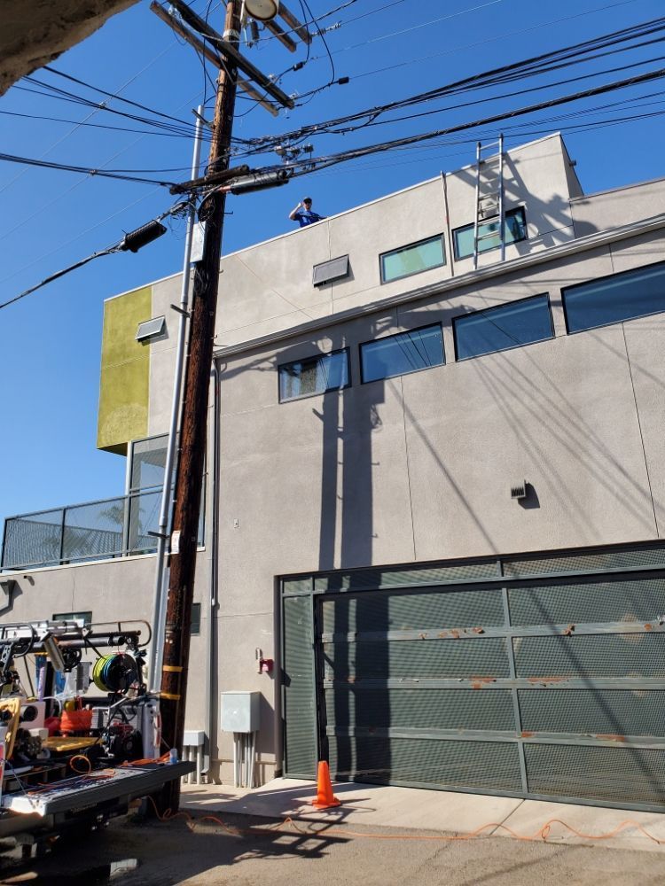 Street view of a building with a utility pole, power lines, and a work truck under a bright blue sky