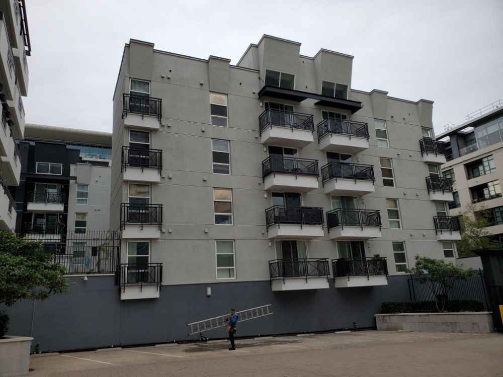 Gray apartment building with balconies and a person standing in the courtyard