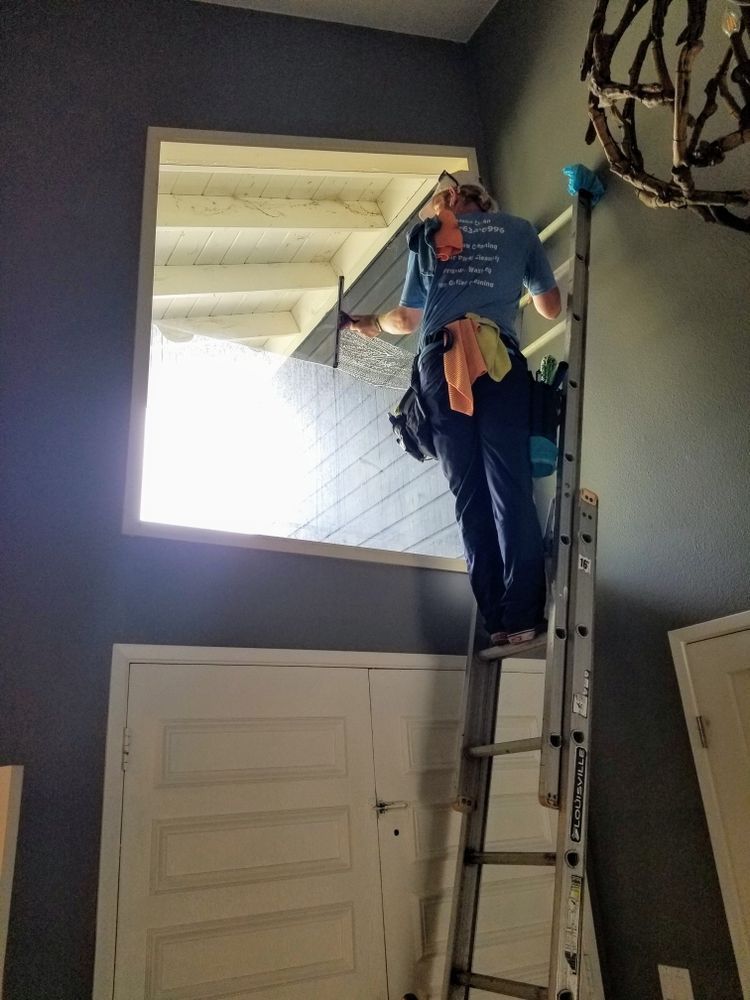 Person on a ladder fixing a ceiling light in a stairwell above a doorway.