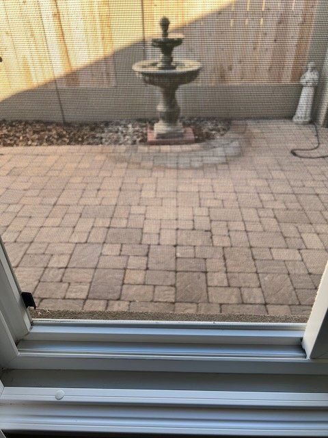 Patio with brick pavers and a small fountain viewed through a sliding glass door