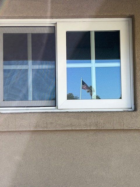 Two apartment windows, one reflecting a U.S. flag in the glass.