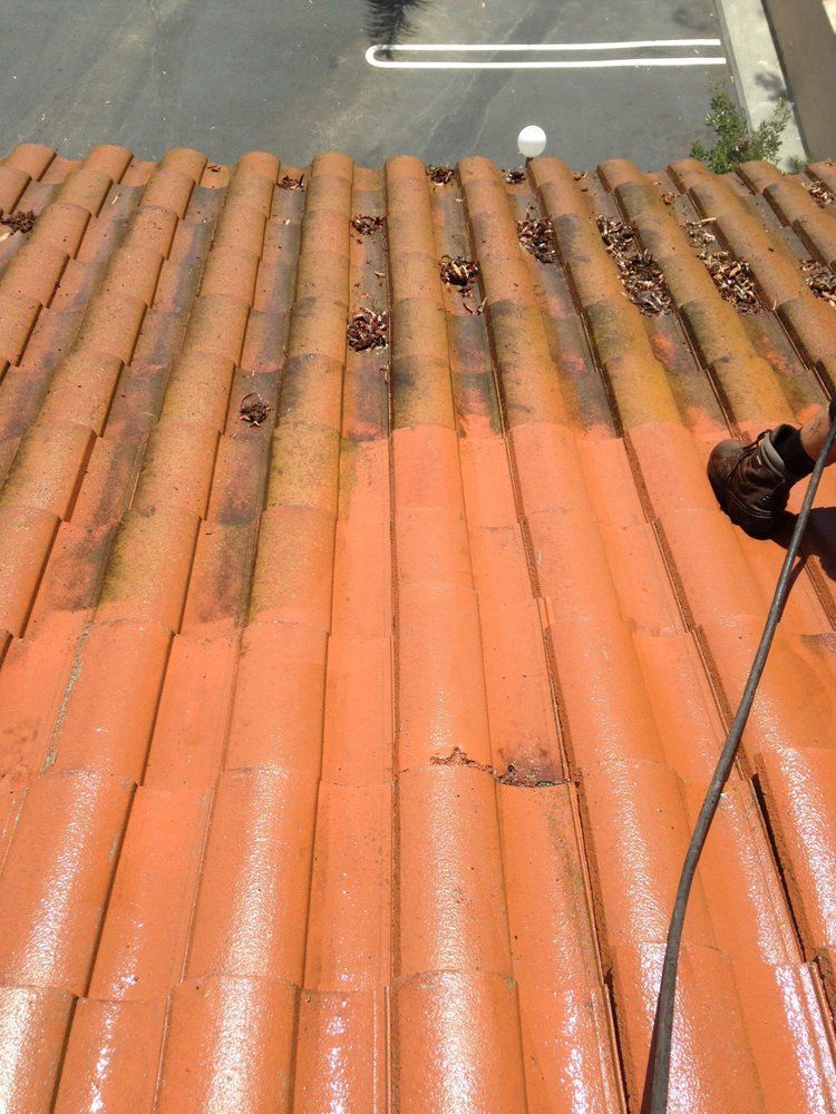 Orange terracotta roof tiles viewed from above, with a parking lot visible at the top edge.