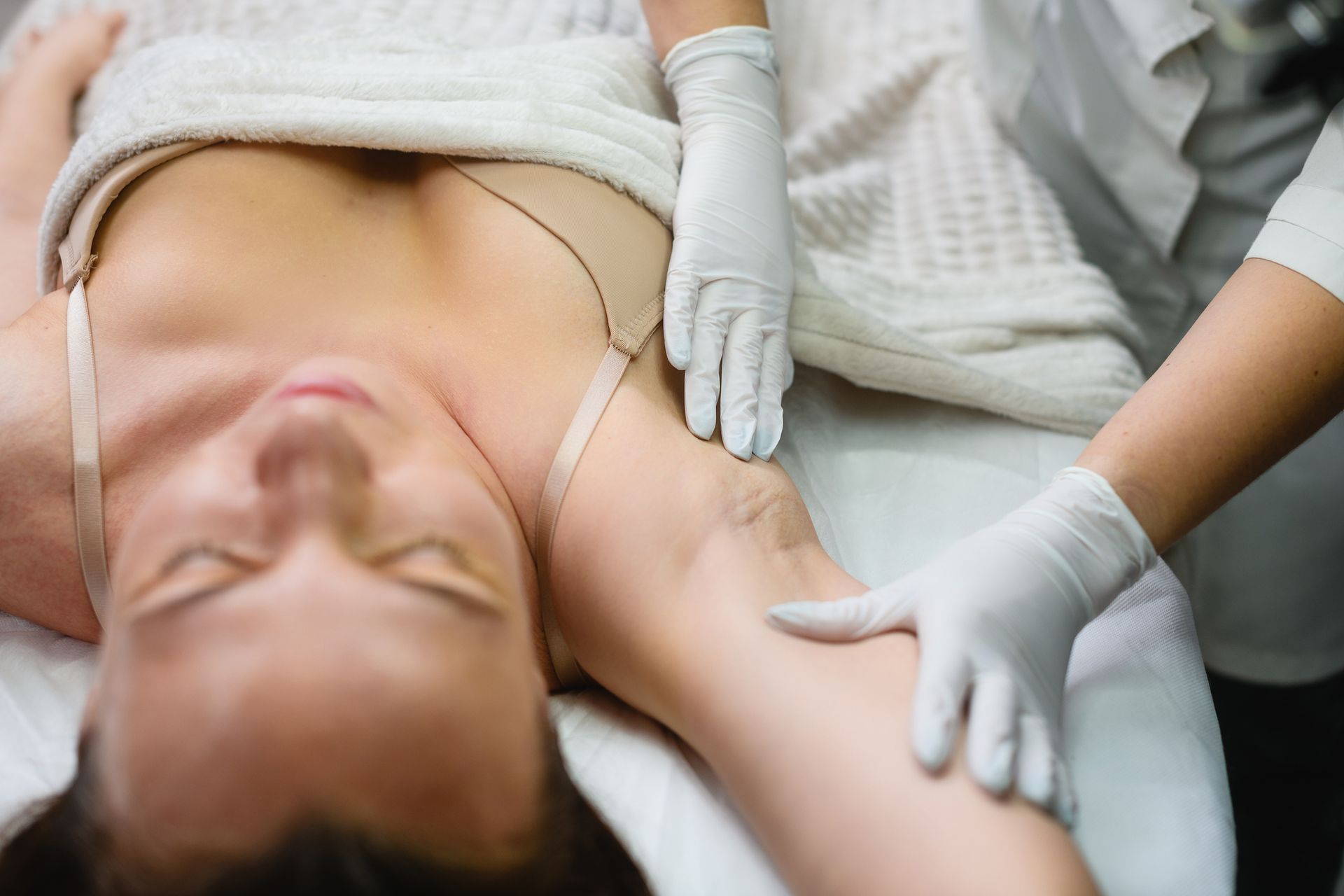 una donna è sdraiata su un letto e riceve un trattamento di depilazione laser a Bergamo alle ascelle