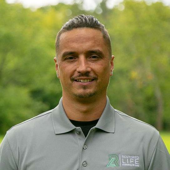 A man in a grey polo shirt is smiling for the camera.