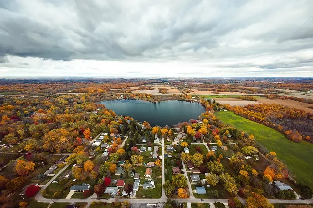 An aerial view of a small town surrounded by trees and a lake.