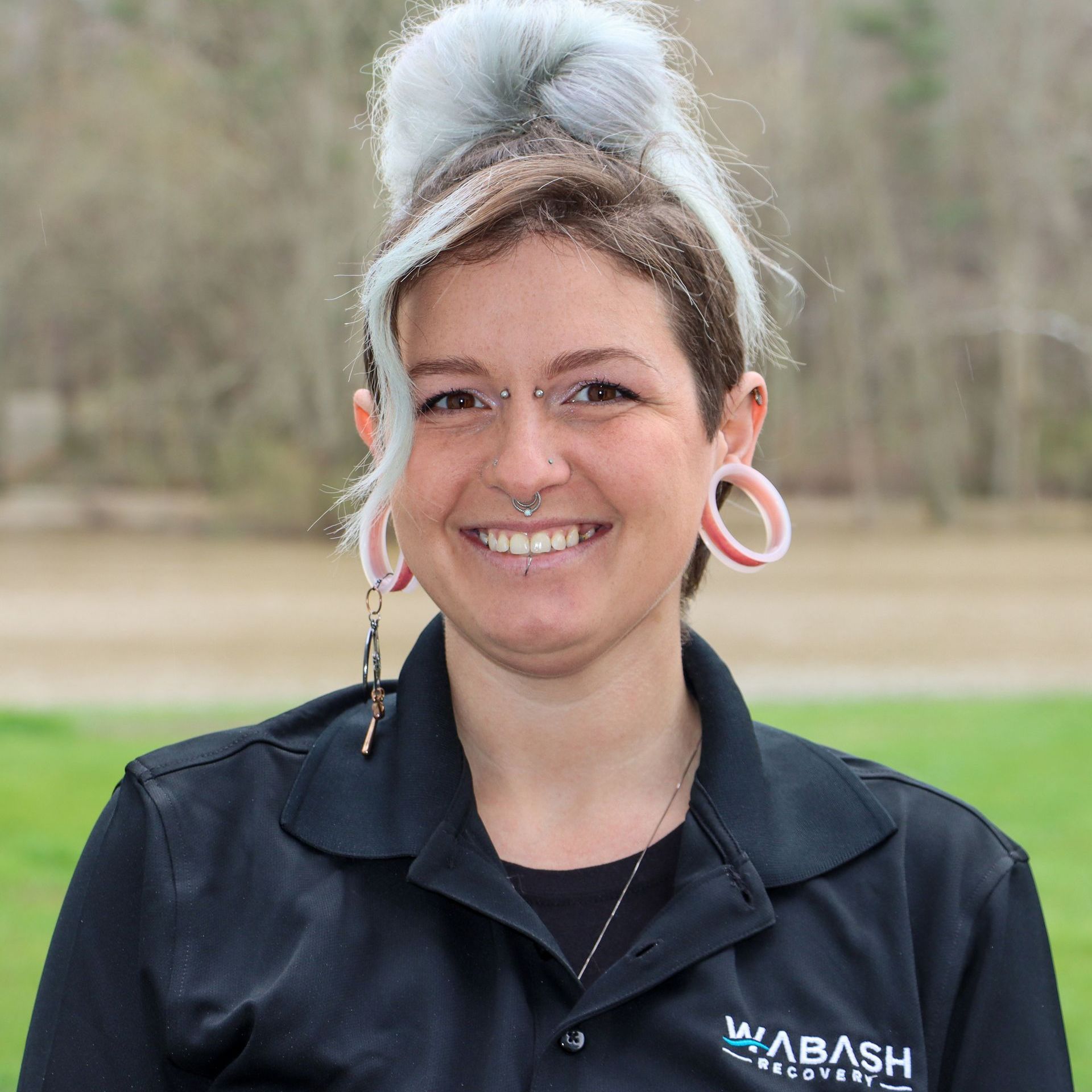 A woman wearing a black shirt and earrings is smiling for the camera.