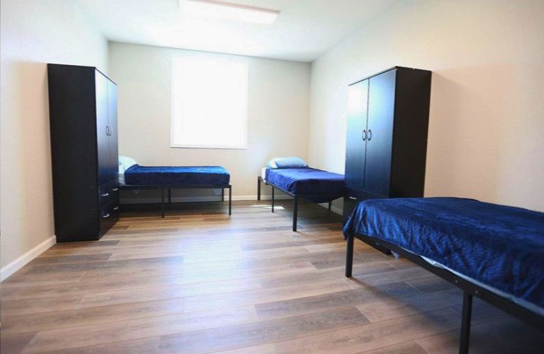 A room with three beds , two wardrobes , and a window.