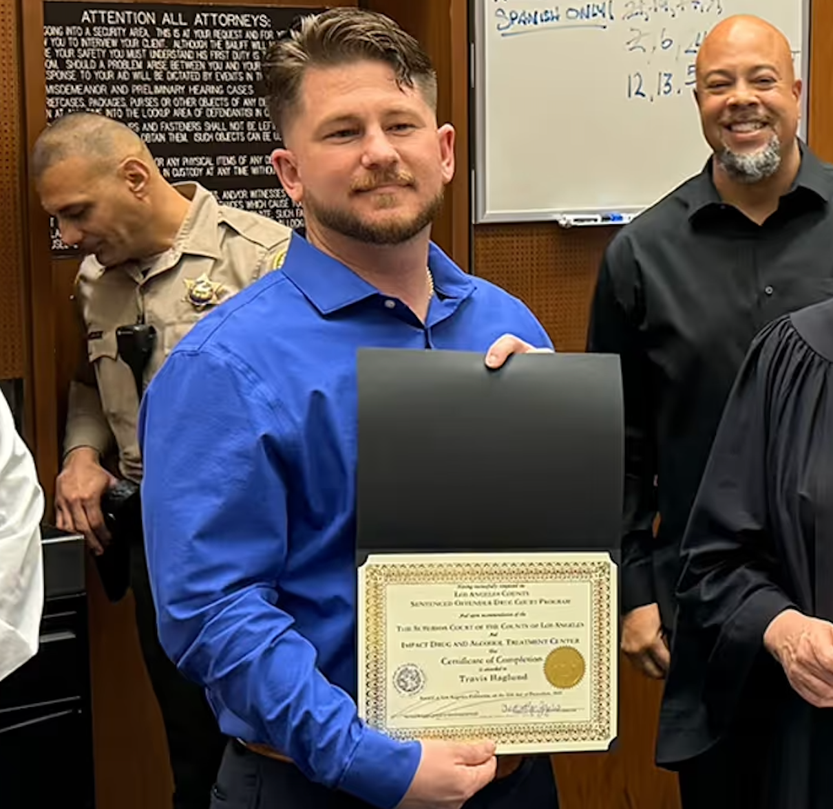 A man in a blue shirt is holding a certificate