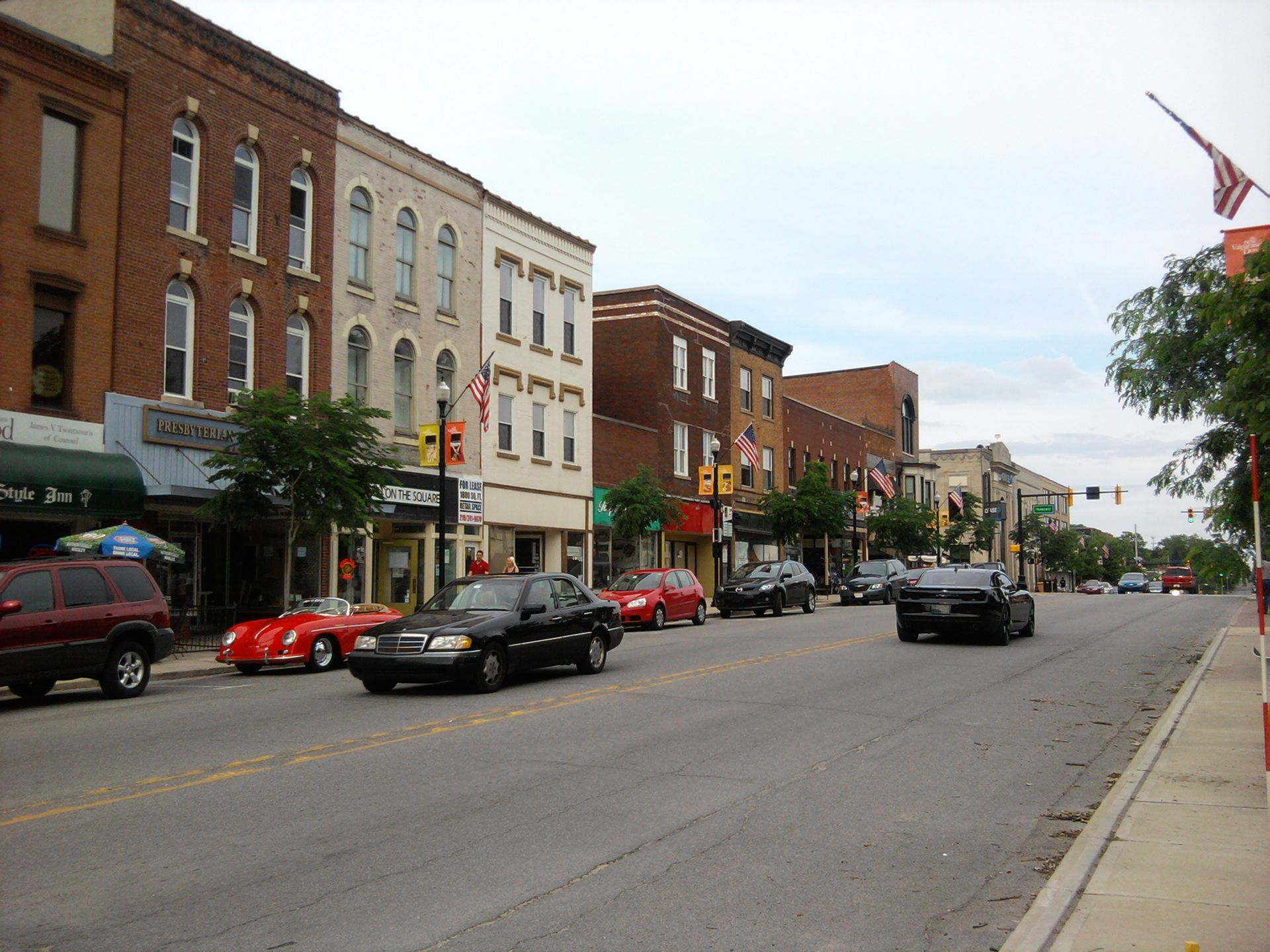 A row of cars are driving down a street in a small town