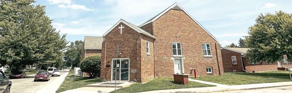 A large brick building with a lot of windows and trees in front of it.