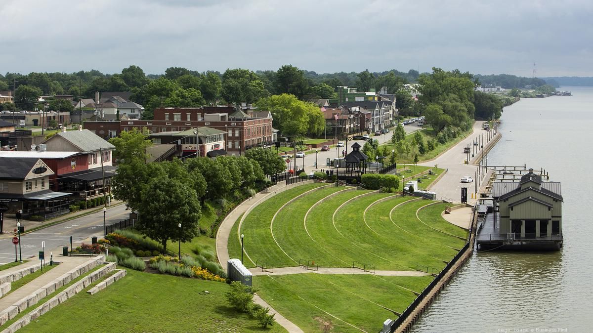 An aerial view of a city along a river with a boat in the water.