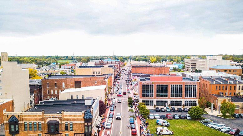 An aerial view of a small town with a lot of buildings and cars driving down the street.