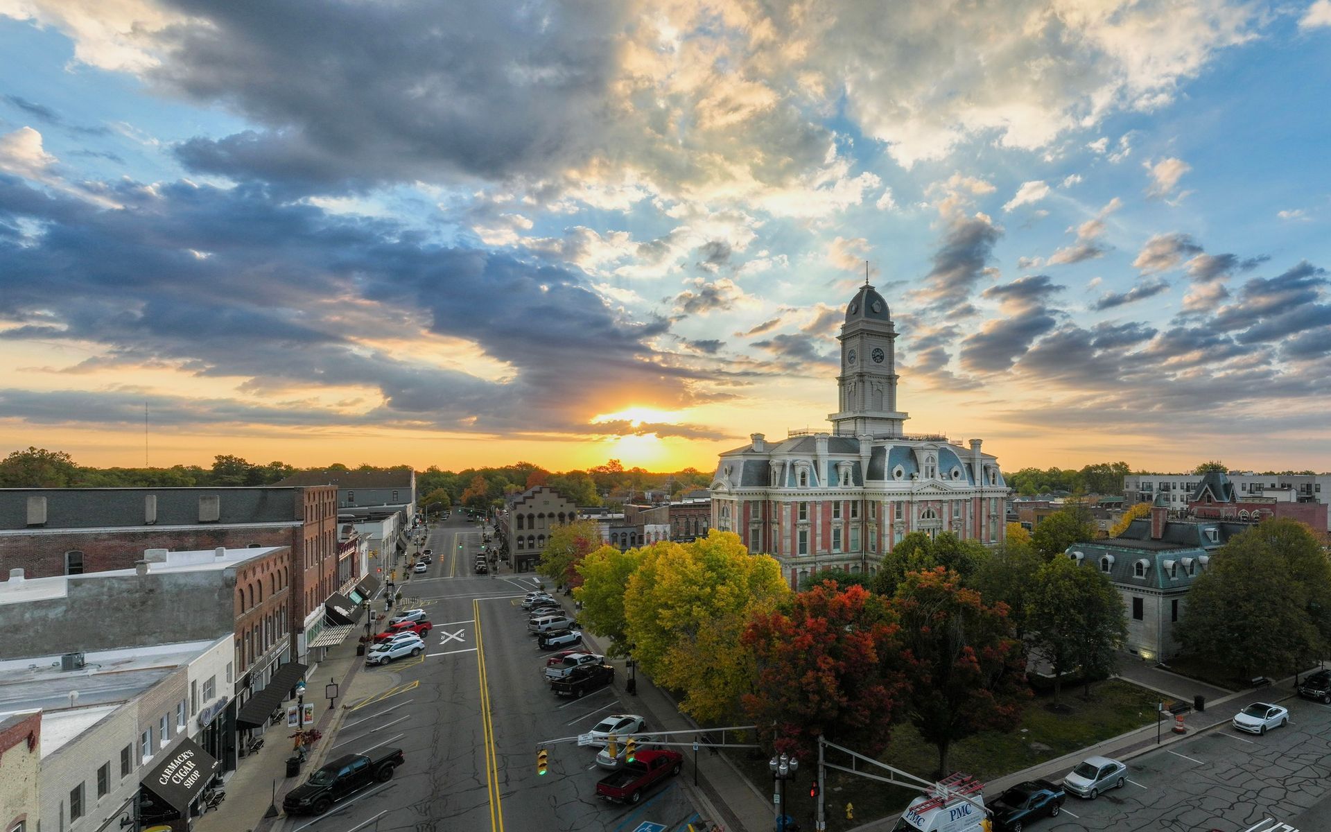 An aerial view of a city at sunset with a courthouse in the foreground.