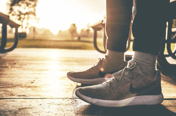 A person is standing on a sidewalk wearing sneakers.