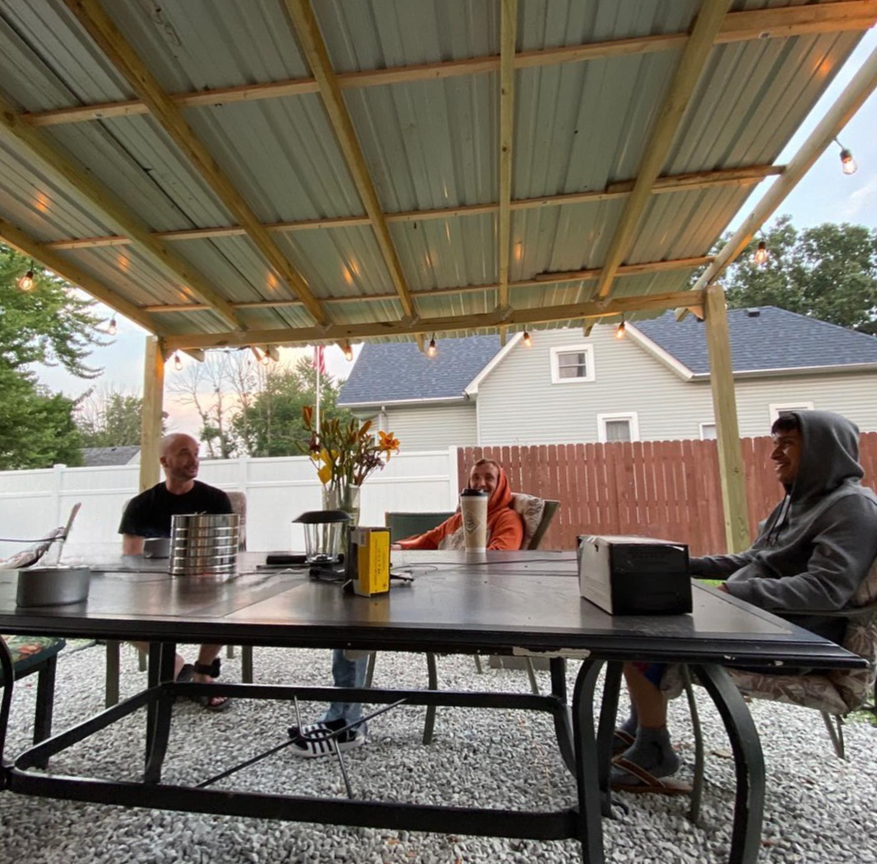 A group of people are sitting at a table under a canopy.