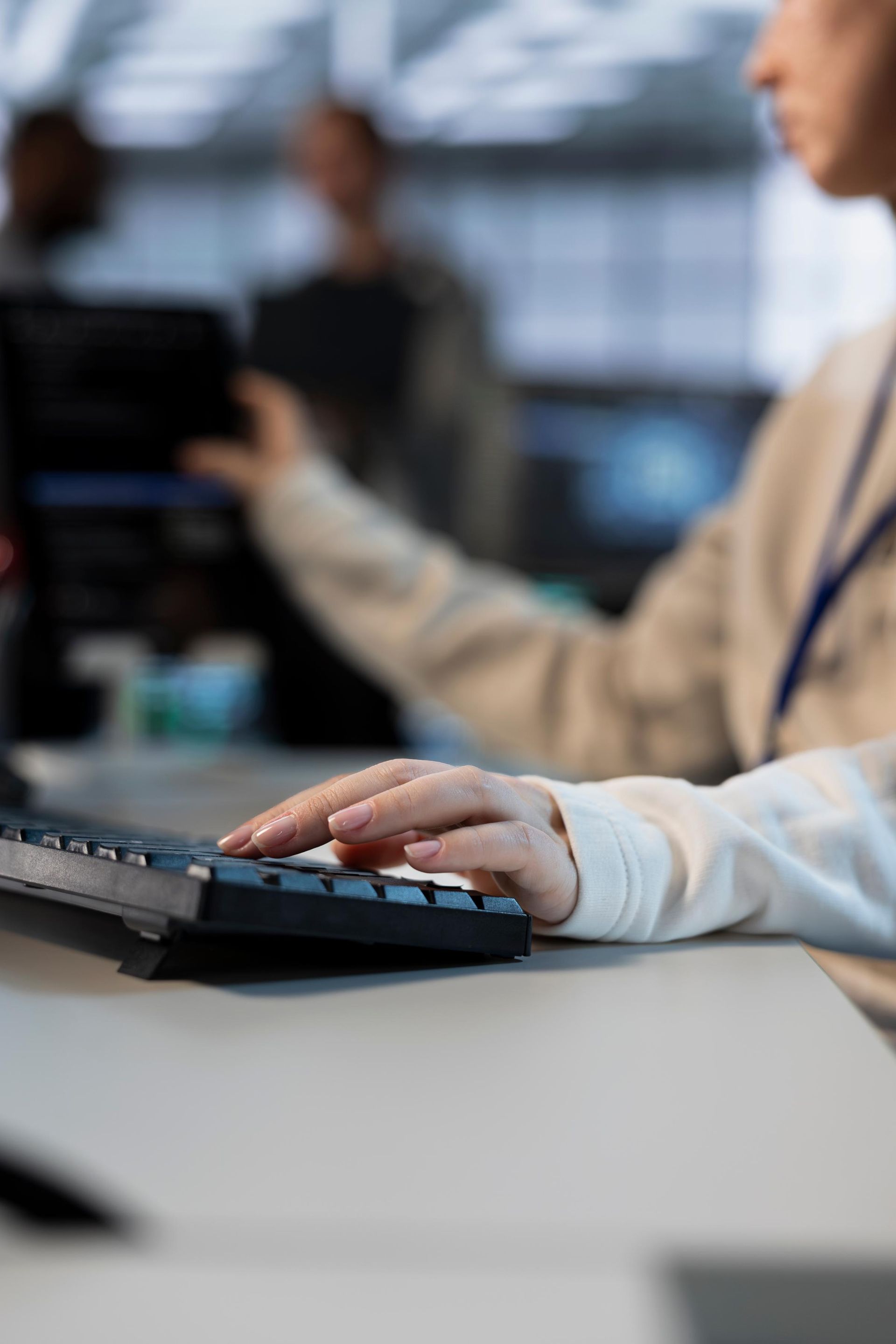 Person's hand typing on a black keyboard at a desk. 
