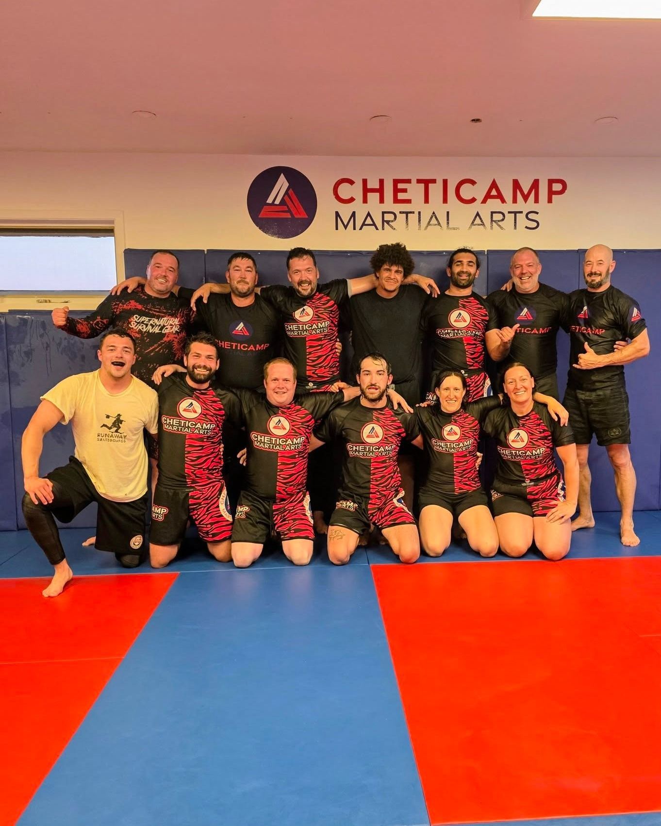 Group photo of martial arts team posing on blue and red mats at Cheticamp Martial Arts dojo