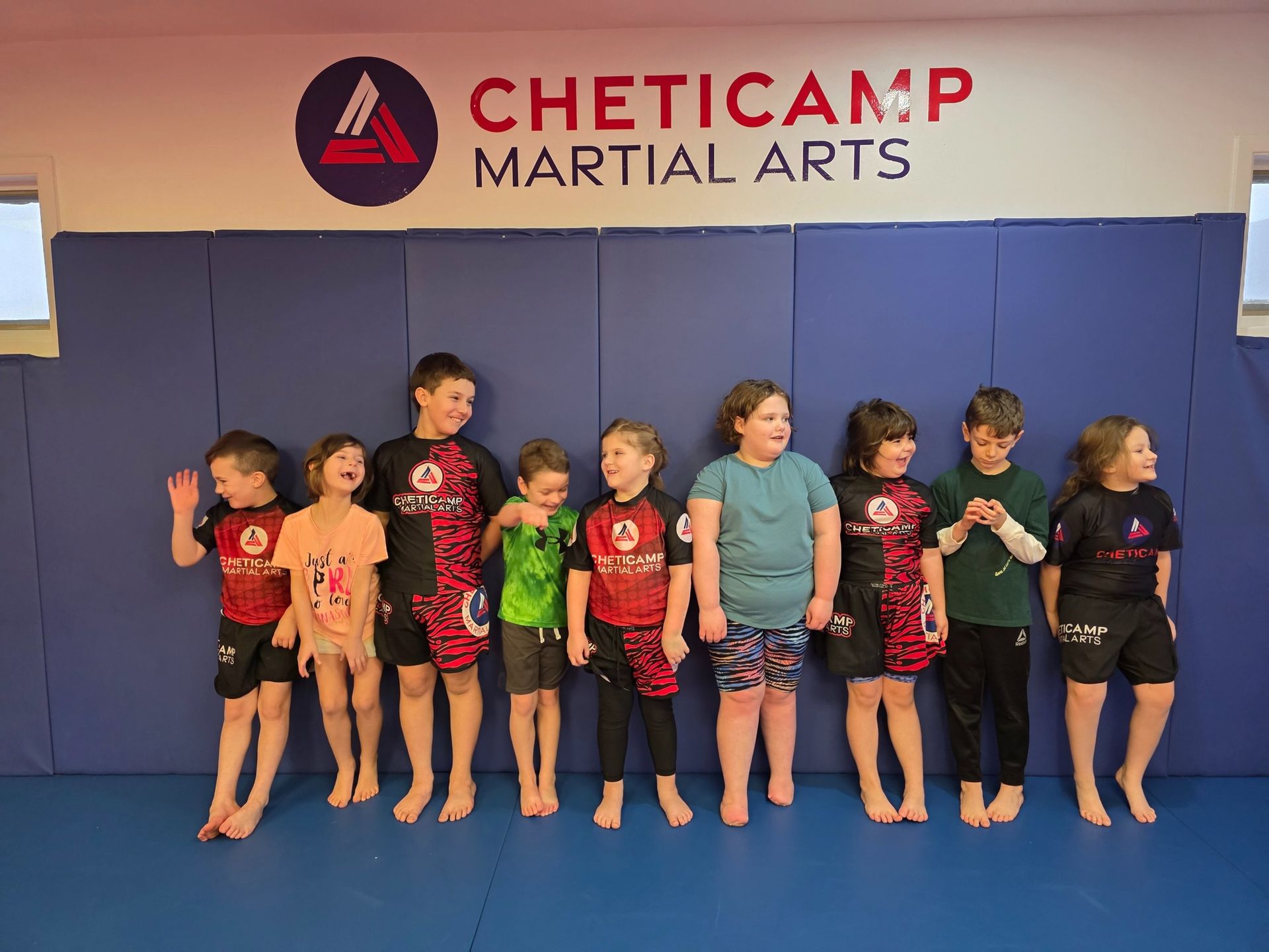 Children standing barefoot in a martial arts studio under a Cheticamp Martial Arts sign