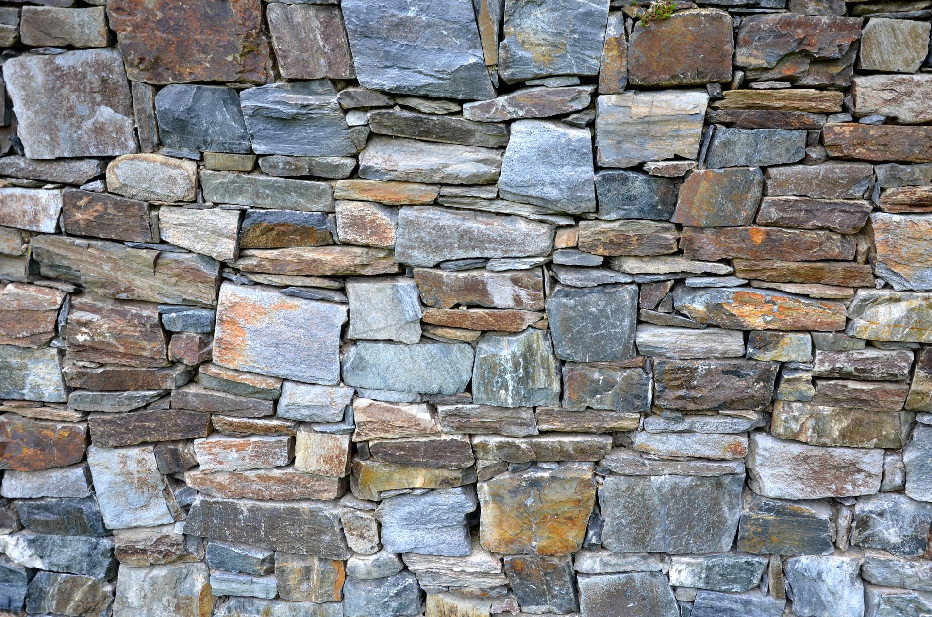 A wall constructed from an array of colourful stones, showcasing various textures and hues A wall constructed from an array of colourful stones, showcasing various textures and hues