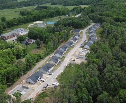 An aerial view of a row of houses that is a condo association surrounded by trees