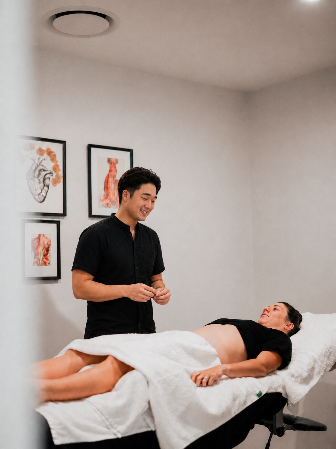 Massage therapist working on a client lying on a treatment table in a bright spa room