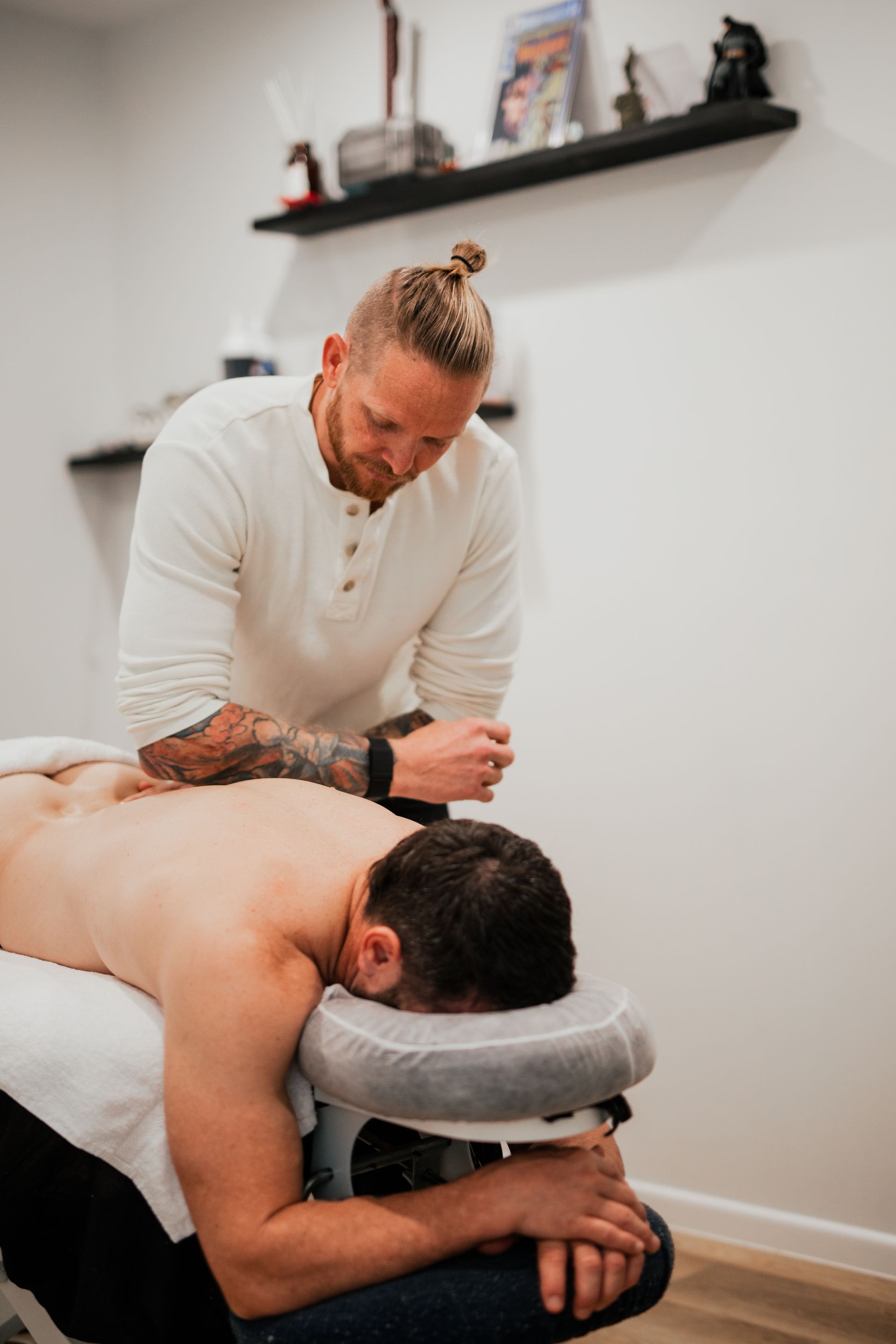 Massage therapist working on a client lying face down on a massage table in a treatment room