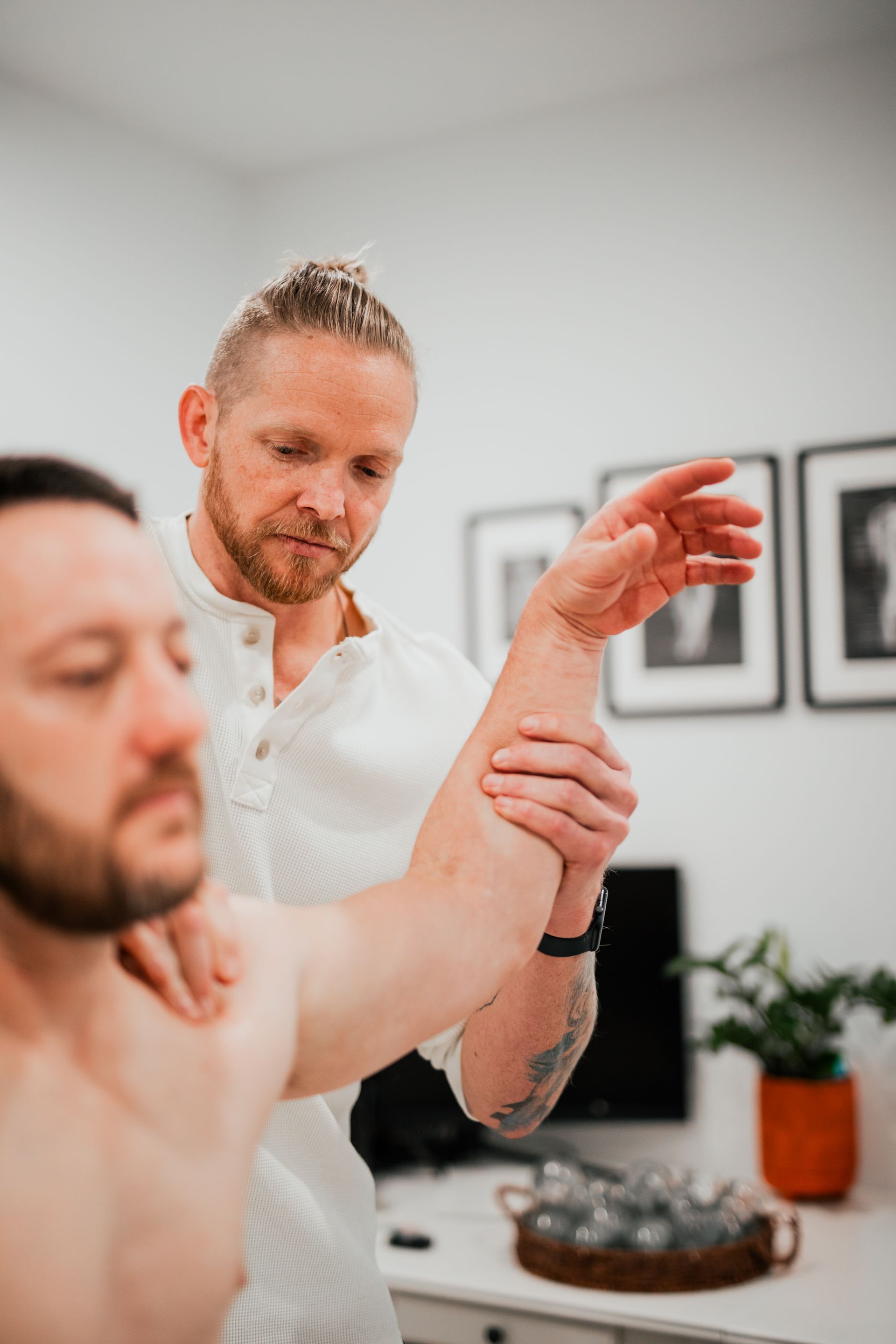 Massage therapist stretching a client’s arm in a bright clinic room