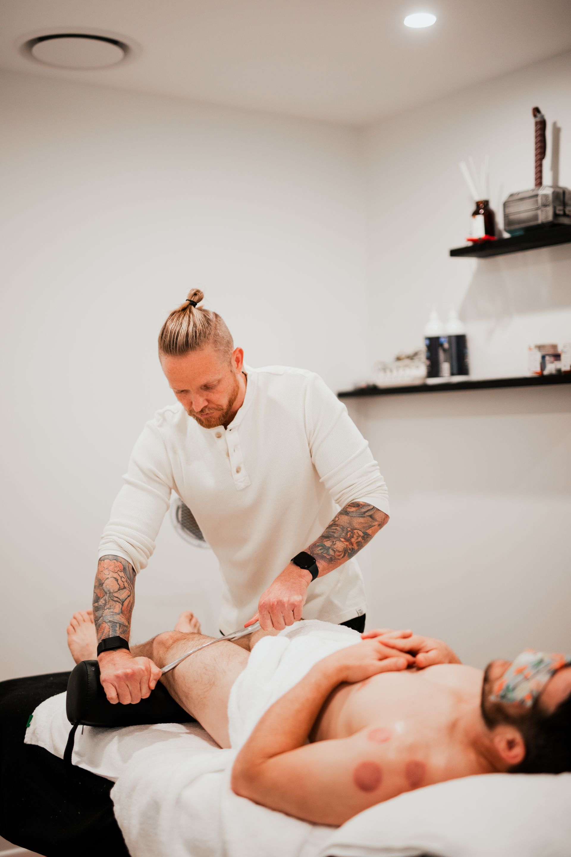 Massage therapist treating a client on a table in a clean spa room