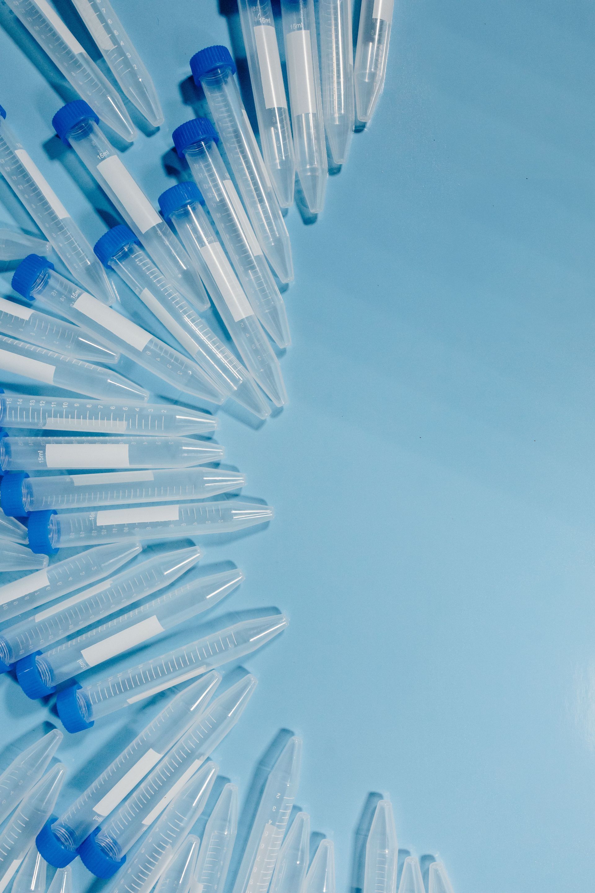 Close-up of clear plastic pipette tips with blue ends arranged in a curved pattern on a blue background