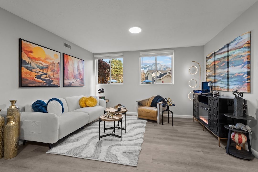Bright living room with white sofa, artwork, striped rug, and a view through large windows