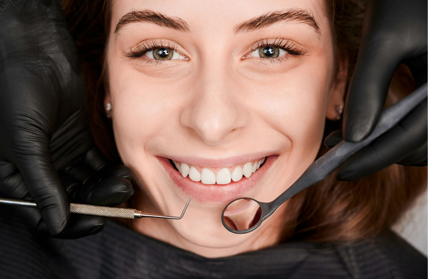 Dentist holding a dental model with teeth, roots, and an implant illustration